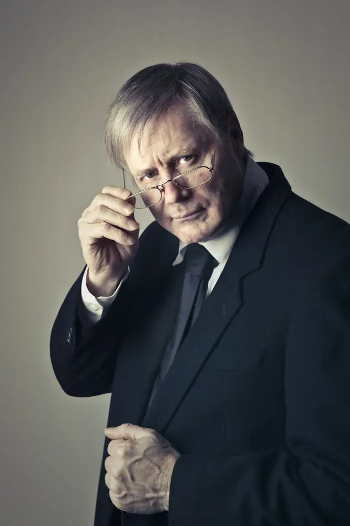 Serious senior adult man with glasses in a suit, conveying professionalism in a portrait shot.