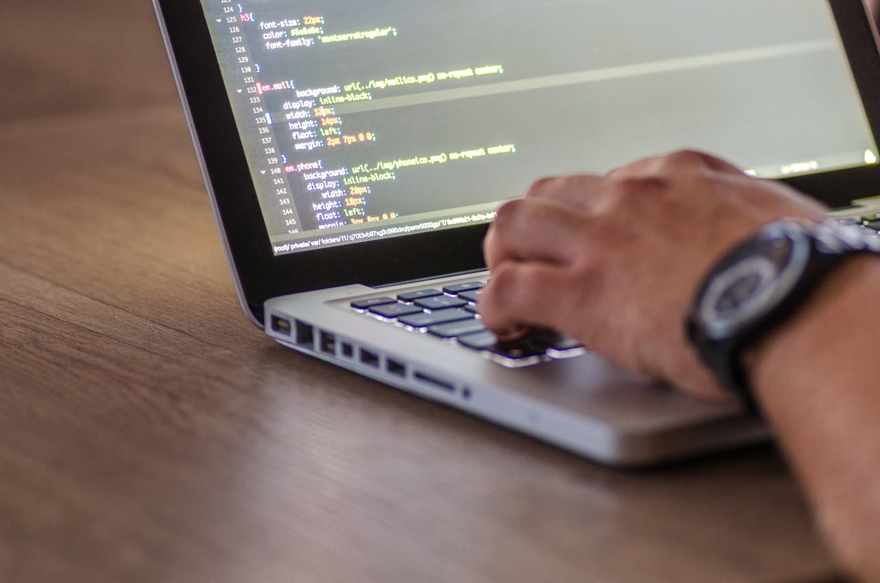 About A close-up shot of a person coding on a laptop, focusing on the hands and screen.